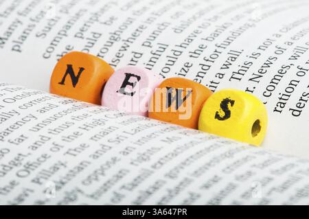 Wort-Nachrichten. Hölzerne Würfel auf Zeitungspapier. Schließen Sie Studio gedreht Stockfoto