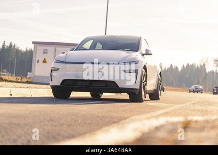 Modernes weißes Auto auf Asphaltstraße mit natürlicher Landschaft im Hintergrund, Tesla, neues Modell Y Juniper, Deutschland, Europa Stockfoto