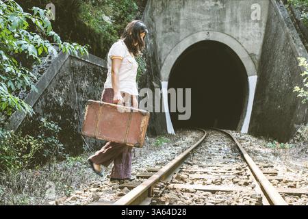 Frau gehen auf Eisenbahn mit einem Koffer in Händen. Vintage-Stil Bild Stockfoto