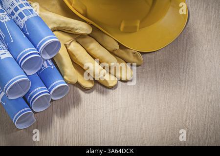 Blauer Blaudruck Rollen Bauhelm Leder Sicherheitshandschuhe auf Holzbrett Baukonzept Stockfoto