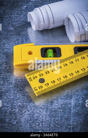 Nahaufnahme des zusammengerollten Blaupausen-Lineals und der Konstruktionsebene auf einem Wartungskonzept mit metallischem Kratzer im Hintergrund Stockfoto