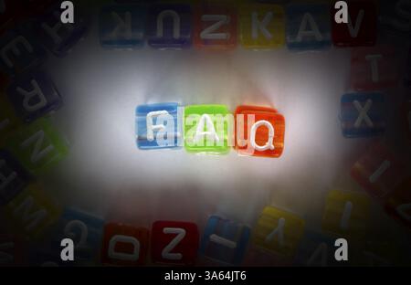 Text FAQ auf bunten Würfel über weiß. Buchstaben weiß zufällig verstreut Stockfoto