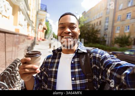 Aufgeregt afroamerikanischen Kerl nimmt Selfie mit Kaffee Stockfoto