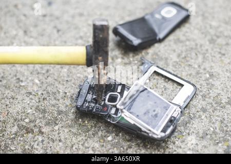 Altes Handy kaputt. Hammer-Falte-Telefon Stockfoto