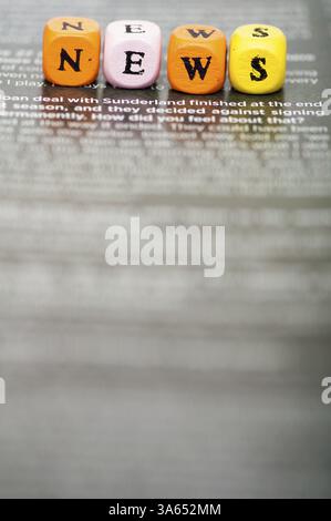 Wort-Nachrichten. Hölzerne Würfel auf Zeitungspapier. Schließen Sie Studio gedreht Stockfoto