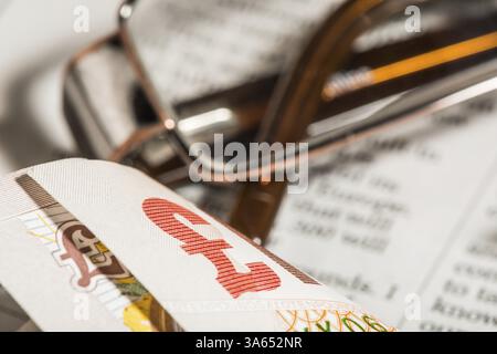 Gläser, Münzen, Kreditkarten und Banknoten auf Zeitungspapier. Makroaufnahme Stockfoto