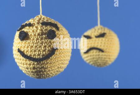 Gestrickte gelbe Emoticons auf blauem Hintergrund Stockfoto