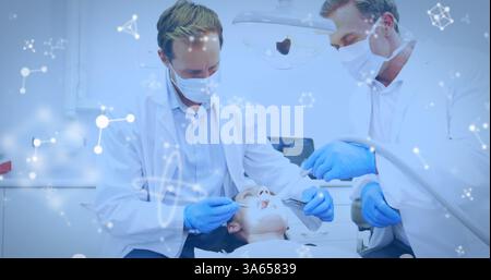 Bild von Molekülen, die über zwei männliche Zahnärzte mit Gesichtsmasken fließen, die Patienten im Zahnarztstuhl behandeln Stockfoto