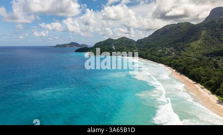 Klares türkisfarbenes Wasser trifft auf einen abgeschiedenen Strand und dichten Wald umgeben von Felsformationen. Grand Anse. Seychellen, Mahe. Stockfoto