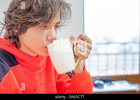 Heiße Schokolade aus einer großen weißen Tasse am Tisch trinken Stockfoto