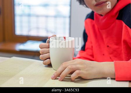 Heiße Schokolade mit Himbeeren aus einer großen weißen Tasse am Tisch trinken Stockfoto