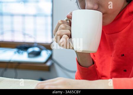 Heiße Schokolade aus einer großen weißen Tasse am Tisch trinken Stockfoto