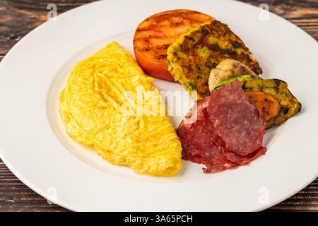 Rustikaler Frühstücksteller mit Spiegeleiern, gegrilltem Gemüse und putenspeck Stockfoto