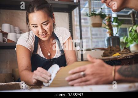 Menschen, Team und Töpferei im kreativen Studio, arbeiten zusammen und schnitzen Ton für keramisches Kunsthandwerk. Unterricht, Ausrüstung und Hilfe beim Unterricht an Stockfoto