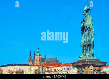Die Bronzestatue des Heiligen Johannes Nepomuk der Karlsbrücke vor dem Hintergrund der mittelalterlichen gotischen Veitskirche in Prag, Tschechien Stockfoto