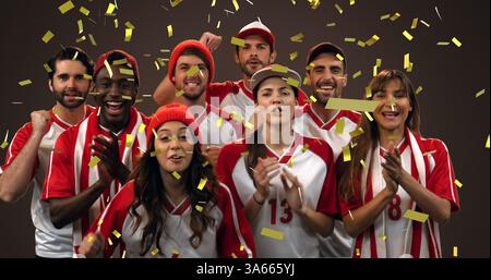 Bild eines Goldkonfetti, das über eine Gruppe männlicher und weiblicher Sportfans fällt Stockfoto