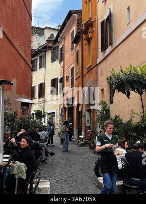 Rom, Italien - März 2025 - Viertel Trastevere, enge Kopfsteinpflasterstraßen, gesäumt von alten Häusern. Nachts strömen Einheimische und Touristen gleichermaßen zu ihrem Mann Stockfoto