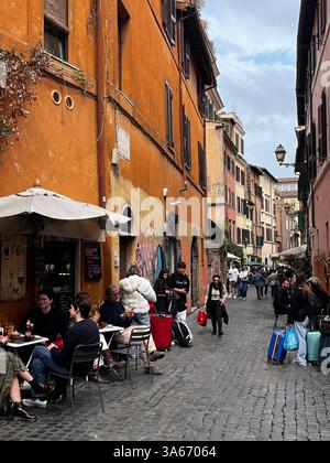Rom, Italien - März 2025 - Viertel Trastevere, enge Kopfsteinpflasterstraßen, gesäumt von alten Häusern. Nachts strömen Einheimische und Touristen gleichermaßen zu ihrem Mann Stockfoto