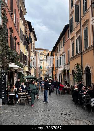 Rom, Italien - März 2025 - Viertel Trastevere, enge Kopfsteinpflasterstraßen, gesäumt von alten Häusern. Nachts strömen Einheimische und Touristen gleichermaßen zu ihrem Mann Stockfoto