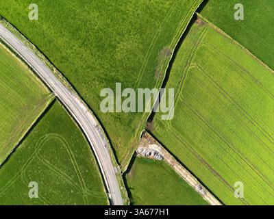 Blick aus der Vogelperspektive auf britisches Ackerland mit grünen Feldern, gewundenen Landstraßen und Trockenmauern, die ländliche Landwirtschaft und ländliche Landschaft zeigen. Stockfoto