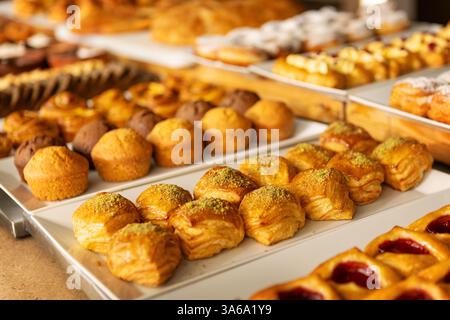 Verschiedene gebackene Gebäckstücke, Muffins und süße Brötchen werden auf dem Buffettisch in einer gemütlichen Bäckerei oder im Café serviert, um Frühstück, Brunch und Dessert Lovers S zu genießen Stockfoto