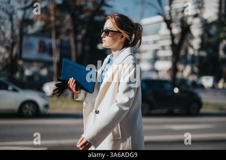 Selbstbewusste professionelle Spaziergänge im Freien mit Mappe und elegantem weißen Mantel Stockfoto