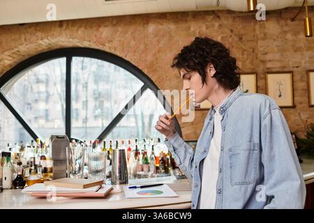 Junger Mann genießt Freizeit in einem trendigen Café, während er über seine Arbeit nachdenkt und einen Drink schlürft. Stockfoto