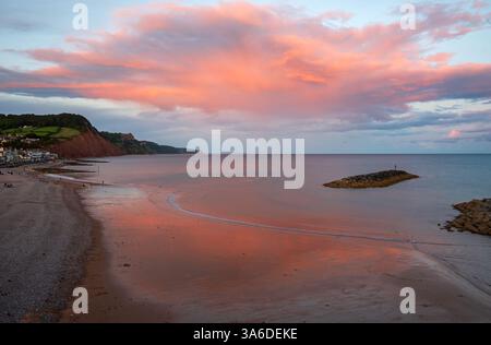 Blick nach Osten vom Aussichtspunkt Sidmouth Beach bei Sonnenuntergang, während die untergehende Sonne die Wolken erhellt. Sidmouth, Devon, England, Großbritannien. Stockfoto