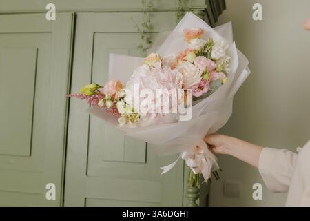 Schönes Mädchen sammelt einen Blumenstrauß in einem Blumenladen, Stockfoto
