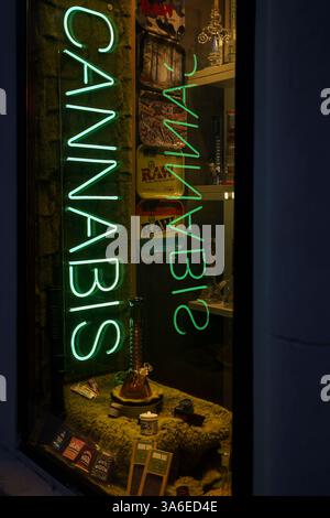 Warschau, Polen. 27. Januar 2025 - Helles Neon-Cannabisschild, das über ausgestellten Produkten in einem Schaufenster leuchtet Stockfoto