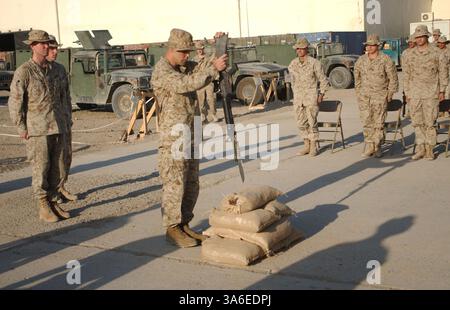 25. August 2004; Mahmudiyah, Irak; Ein Marine mit Kompanie E, 2. Bataillon, 2. Marine-Regiment, bereitet sich darauf vor, während einer Gedenkfeier am 25. August ein Gewehr in Sandsäcke zu setzen. Die Zeremonie war für CPL Christopher W. Belchik, einen Truppenführer der Firma. Er starb am 22. August an Schrapnell-Wunden. Stockfoto
