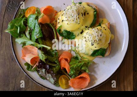 Blick von oben auf einen Frühstücksteller mit Eiern benedict, geräuchertem Lachs und frischem Grünsalat Stockfoto