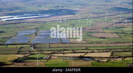 Ein Blick aus der Vogelperspektive auf große Distributionslager östlich von Rugby, West Midlands, UK, neben einer Stromquelle für einen Solarpark und Windturbinen Stockfoto