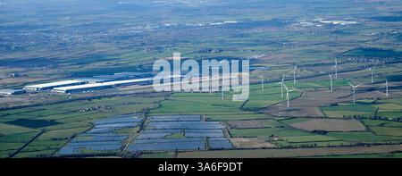 Ein Blick aus der Vogelperspektive auf große Distributionslager östlich von Rugby, West Midlands, UK, neben einer Stromquelle für einen Solarpark und Windturbinen Stockfoto