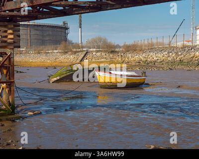 Zwei Boote schwimmen in einem schlammigen Fluss. Eine ist gelb und die andere grün. Die Szene ist ruhig und friedlich Stockfoto