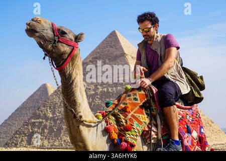 Kulturelle und historische Entdeckungen in Gizeh Ägypten mit einem Kamelreiter in traditioneller Kleidung in der Nähe der majestätischen Pyramiden Stockfoto