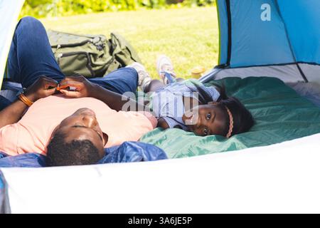 Vater und Tochter entspannen sich im Zelt und genießen gemeinsam Camping im Freien Stockfoto