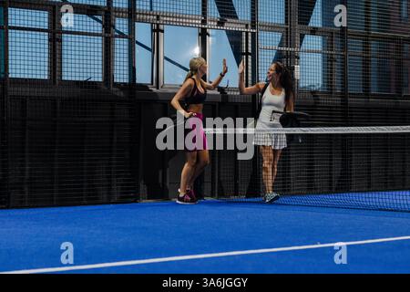 Frauen feiern den Sieg mit High Five auf dem Padel-Tennisplatz Stockfoto
