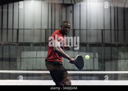 Athletischer Mann, der Padel-Tennis spielt, konzentriert sich darauf, Ball mit Schläger zu schlagen Stockfoto