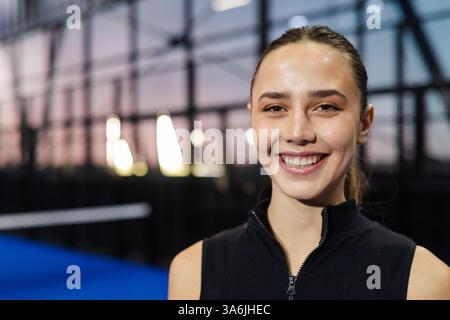 Lächelnde Frau genießt Padel-Tennis-Match auf einem modernen Hallenplatz, Kopierraum Stockfoto