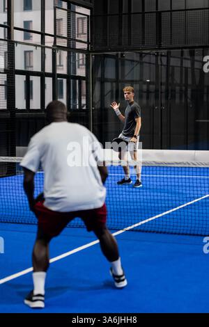 Zwei Männer spielen Padel-Tennis auf dem blauen Platz, fokussiert und konkurrenzfähig Stockfoto