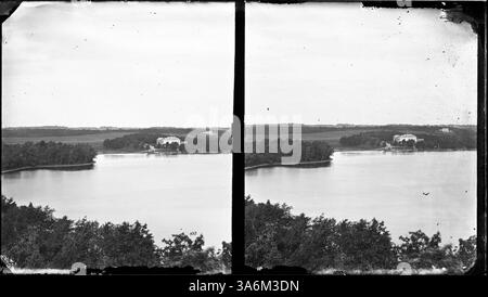 Ein Haus, das über das Wasser sichtbar ist, bietet einen malerischen Blick auf den Comer See in St. Paul, Minnesota. Das Foto fängt die Ruhe des Sees und der umliegenden Landschaft ein. Stockfoto
