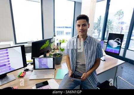 Junger Mann im modernen Büro mit Tablet, umgeben von digitalen Bildschirmen Stockfoto
