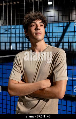 Selbstbewusster Mann, der mit gekreuzten Armen auf dem Padel-Tennisplatz steht Stockfoto