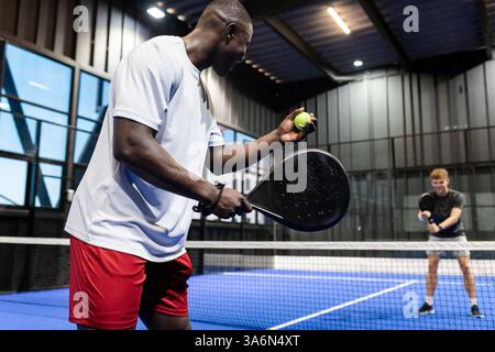 Padel-Tennis im Haus, zwei Männer genießen Wettkampf auf dem blauen Platz Stockfoto