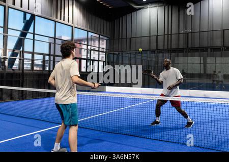 Zwei Männer spielen Padel-Tennis auf dem Hallenplatz und konzentrieren sich auf Ball Stockfoto