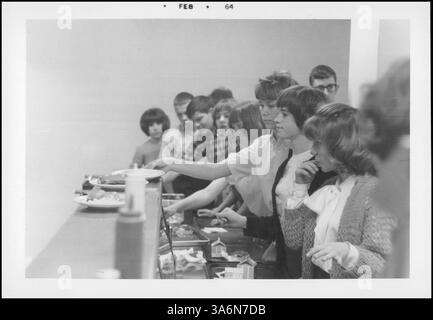 Dieses Bild zeigt das Schulmittagsprogramm, das den Schülern ausgewogene, nahrhafte Mahlzeiten bot und die Verteilung von Milch und Mittagessen während des Schuljahres 1963-1964 hervorhebt. Stockfoto