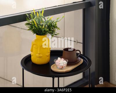 Eine stilvolle und ästhetische Tischeinrichtung mit einer schönen gelben Vase und einer gemütlichen Kaffeetasse Stockfoto
