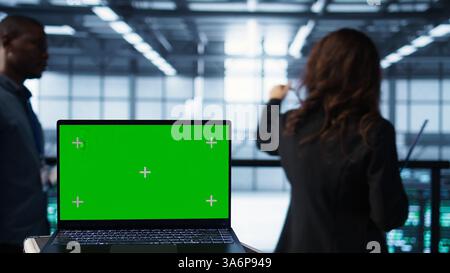 Erstellen Sie einen Laptop vor Softwareentwicklern, die im Rechenzentrum laufen und die Gerätediagnose überprüfen. Nahaufnahme eines Notebooks mit isoliertem Bildschirm neben Teamwork-IT-Experten in der Serverfarm Stockfoto