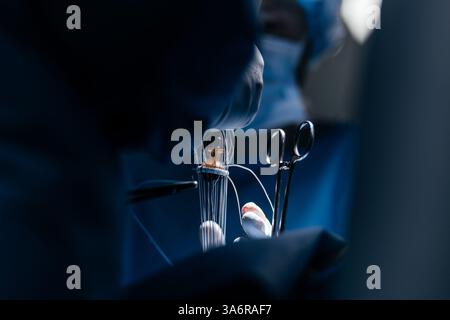 Team erfahrener Chirurgen, die eine komplexe Herzoperation mit voller Konzentration in einem gut beleuchteten Operationssaal durchführen. Technologie in der Kardiologie Stockfoto